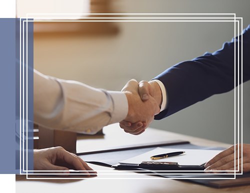 Two professionals shaking hands over a desk